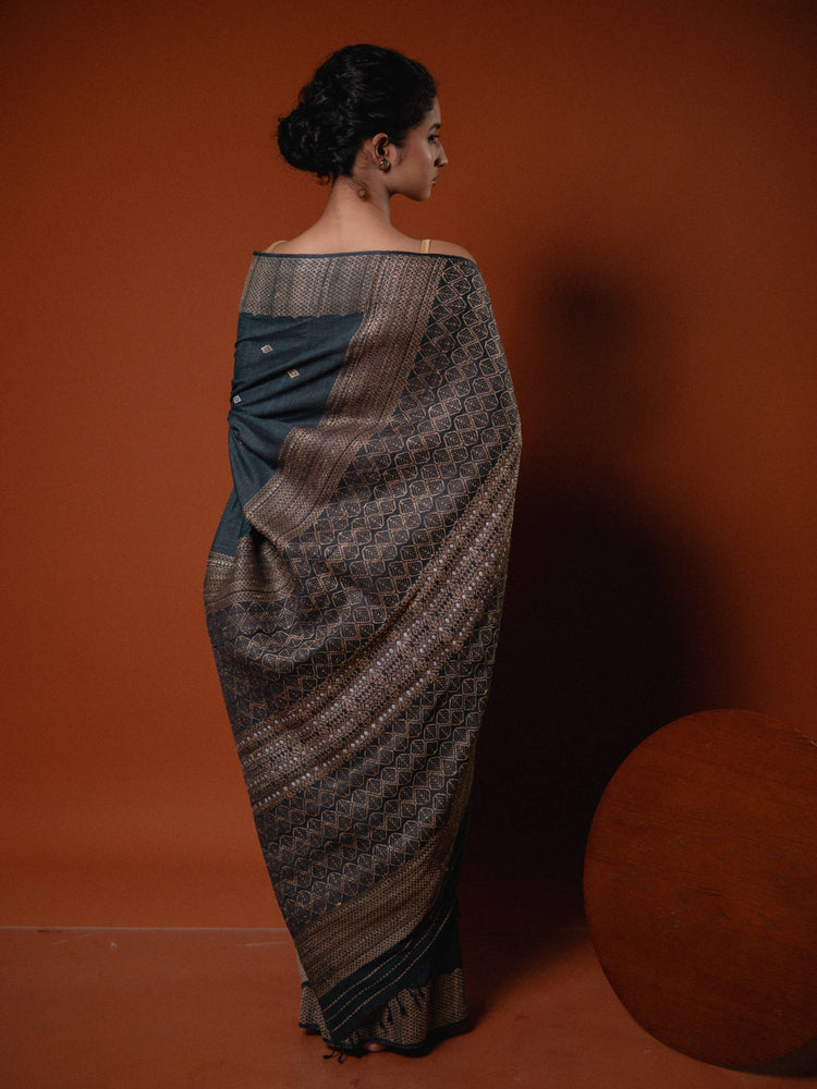 Woman wearing a patterned saree against an orange background