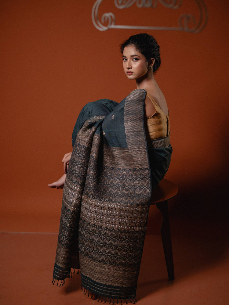 Woman draped in a traditional patterned fabric against an orange background