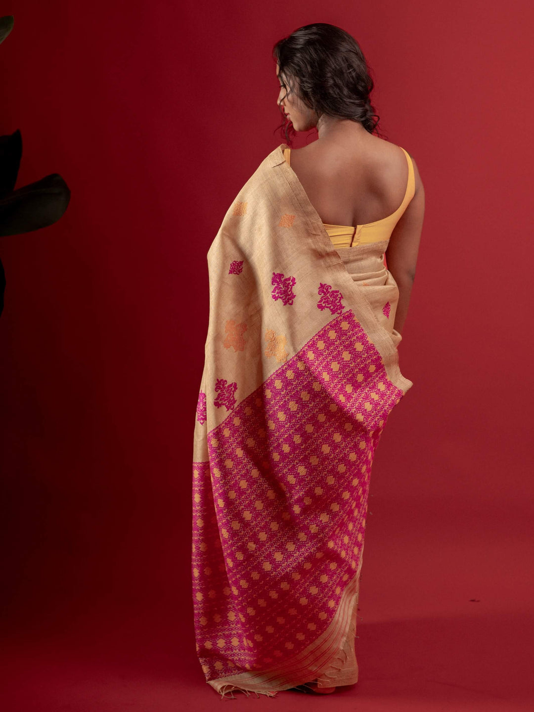 Woman wearing a traditional saree with a red and beige pattern on a red background