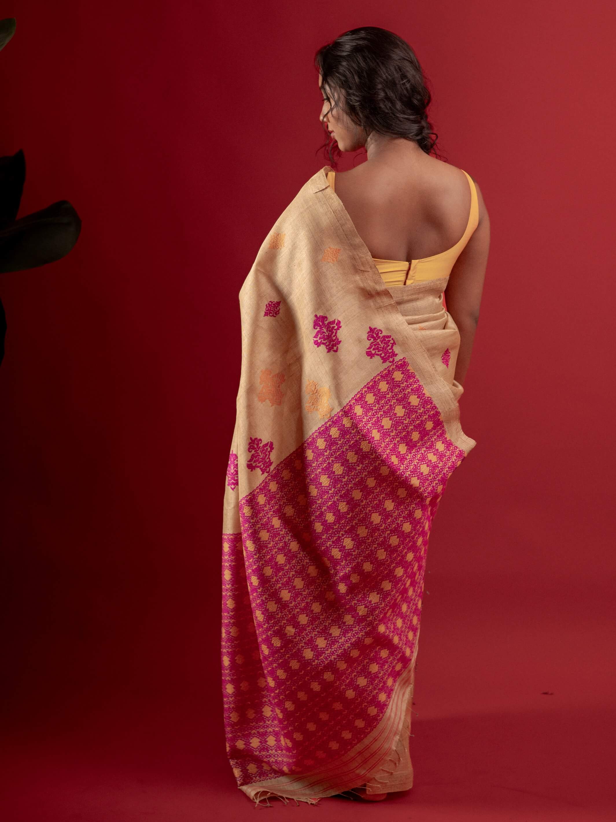 Woman wearing a traditional saree with a red and beige pattern on a red background