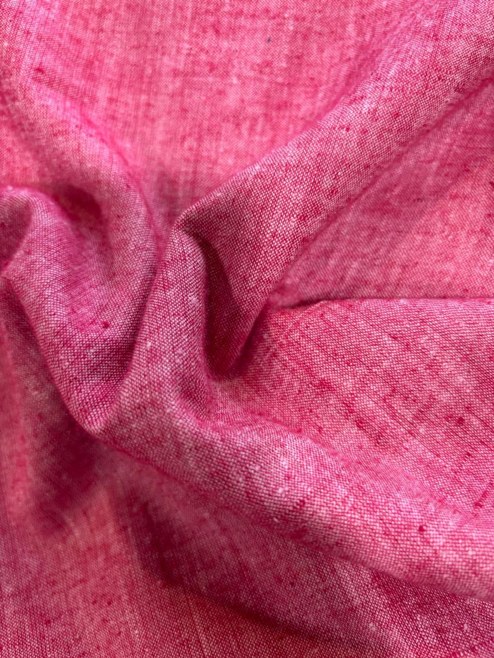 A close-up of draped pink fabric with a visible woven texture and soft folds.